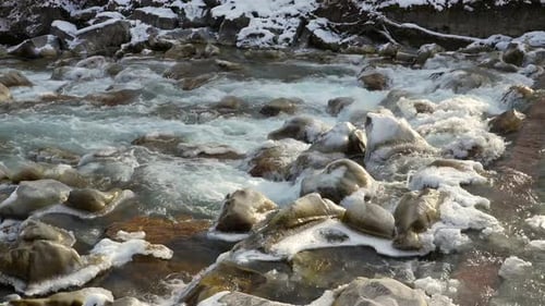 Relajante río de invierno que fluye a través de rocas heladas en el bosque nevado