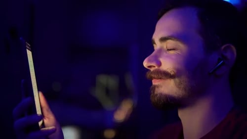 Closeup View of Man Turning Song on Smartphone and Listening to Music By Wireless Earbuds