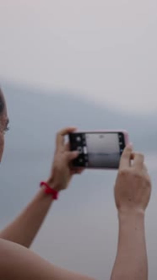 Young Woman Takes a Photo of a Lake with Her Mobile Phone