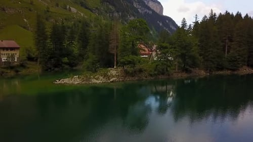 upward flight over a lake revealing a big house in the background between some trees