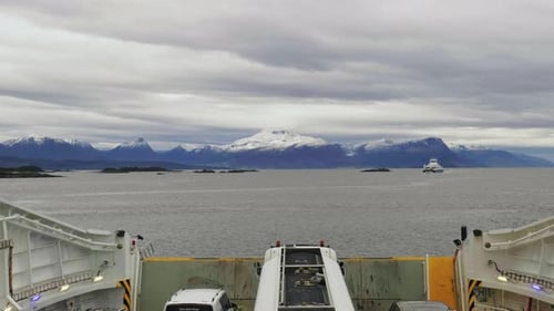 POV From A Ferry Boat Cruising On Norwegian Fjord With View Of Snowy Mountains On A Cloudy Day. wide