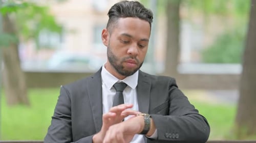 Man in Suit Checks Watch Outdoors