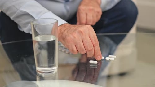 Adult Reaching for Pills Next to Water