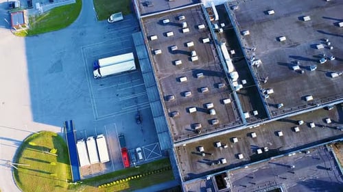 Aerial shot of industrial warehouse. Loading hub and many trucks with cargo trailers. Aerial view of