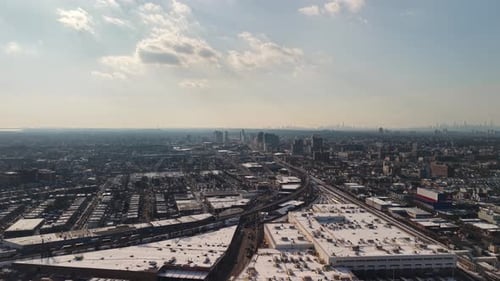 High altitude drone footage capturing an expansive urban area with snow covered rooftops,