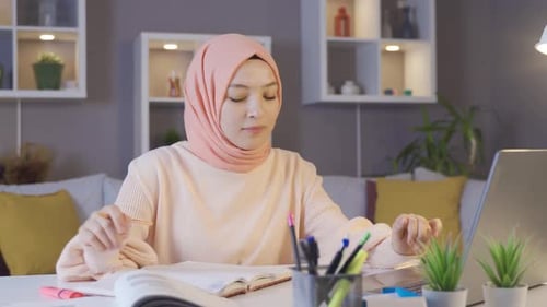 Muslimische Studentin, die mit Laptop und Büchern studiert.