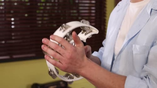 Man playing tambourine in studio, closeup view
