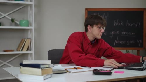 Young Adult Studying at Desk with Laptop and Books