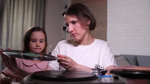 Woman and Child Examining Vinyl Record at Home