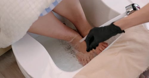 Close-up of feet being rinsed with warm water as part of a pedicure service at nail spa. The elderly