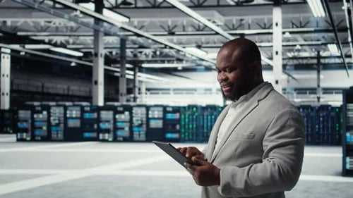 Engineer Working in Server Farm Using Tablet to Analyze Data