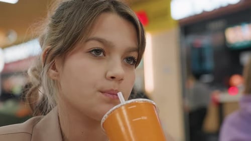 Teenage Girl Sipping Soda in a Restaurant