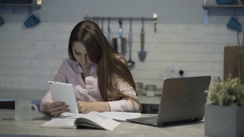 Young student studying online with tablet and notebook in a cafe