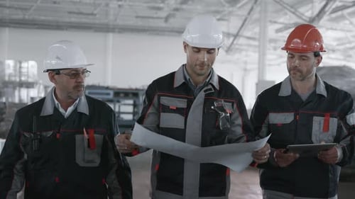 Trois ingénieurs planifient le processus de fabrication de la machine. Ouvrier de sexe masculin portant un casque