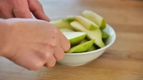 Geschnittene Birne. Obst schneiden. Mit den Händen Birnenscheiben von einem Teller nehmen.