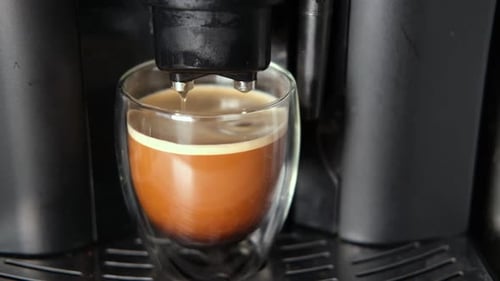 Espresso Pouring Into Glass Cup From Machine