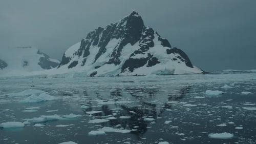 Langsame Fahrt durch antarktische Gewässer mit Spiegelung schneebedeckter Berge im Hintergrund
