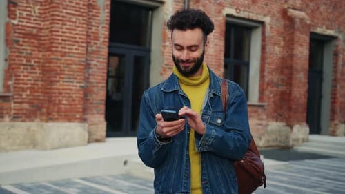 Man Uses Phone on City Street