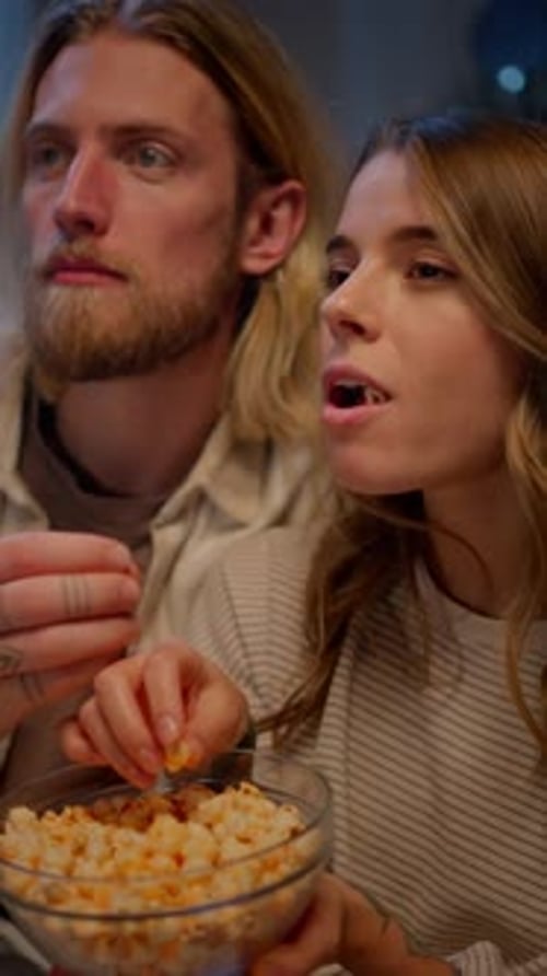 Couple Eating Popcorn While Watching a Movie at Home