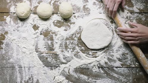 Hands Stretching Dough with Rolling Pin