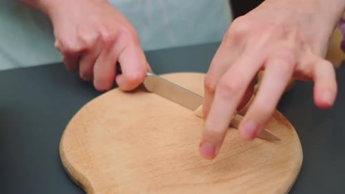 Garlic Being Sliced on Cutting Board with Knife