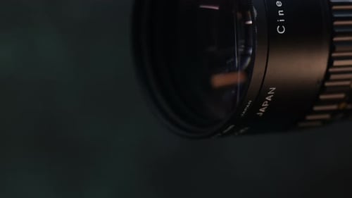 Dolly-right close-up of an old analog Super 8 camera lens on a dark background