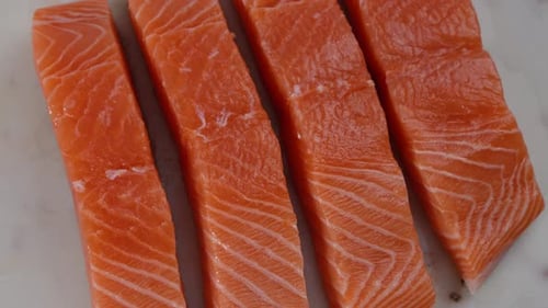 Salmon is cut into pieces. Salmon is rotating on a cutting board.