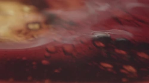 Amber liquid getting filled with other liquid, creating small air bubbles. Abstract macro shot. Expe