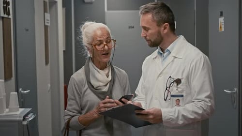Senior Woman Talking to Doctor in Hall