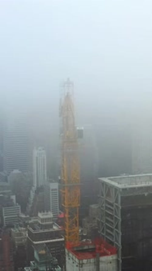 Zumbido vertical dando vueltas alrededor de una grúa de construcción en medio de la brumosa zona de Midtown, Nueva York