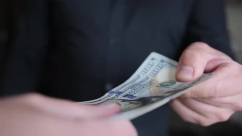 Close-up two people can not share the money pull each other pack of 100 dollar bills.