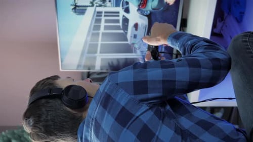 Hombre con auriculares que juega juegos de televisión en línea con un joystick inalámbrico