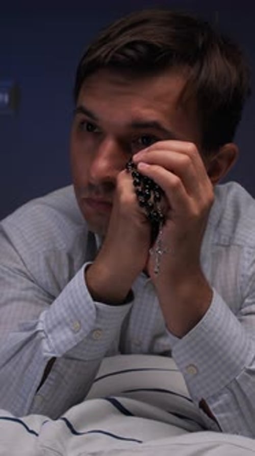 Man Holds Rosary and Prays in Bed