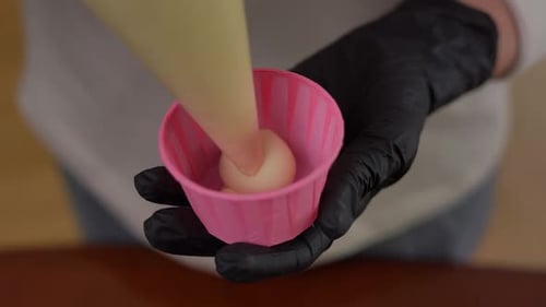 Closeup High Angle View Female Hand Pouring Dough in Cupcake Form Indoors