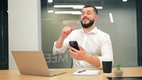 Joyful Businessman Celebrating Success After Receiving Good News on Smartphone