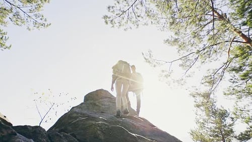 Hiking Couple Climbs Rocky Peak in Forest