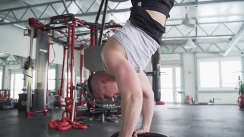 Strong athlete with prosthetic leg standing on hands on calisthenics bars at the gym in slow motion