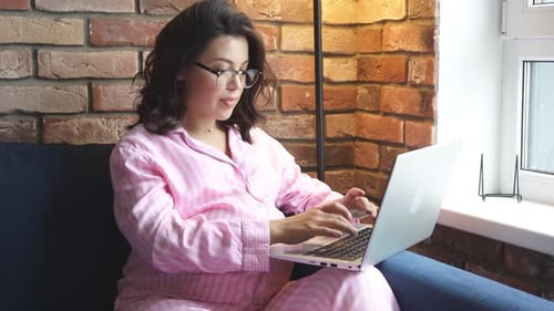 Attractive Pregnant Woman is Sitting with a Laptop at Home