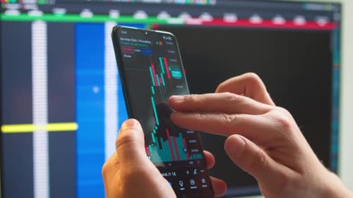 Hands with a Mobile Phone Checking Stock Market Data