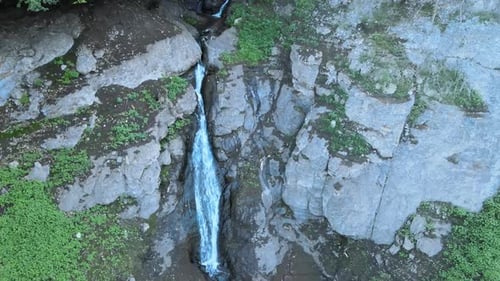 Aerial View of Waterfall Flowing Down Rocky Cliff