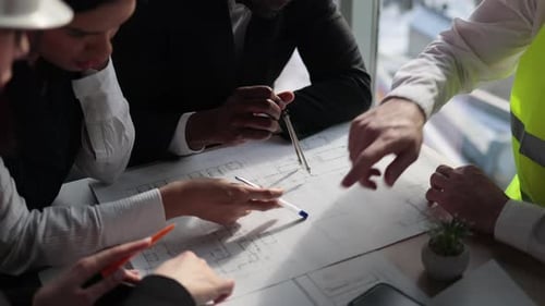 Close Up of Architects Engineers and Designers Sitting Together at Table and Analysing Blueprints