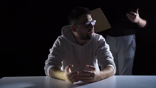 Man Interrogated Under Spotlight at Table