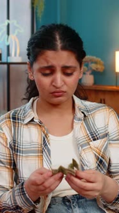 Woman Sadly Looking at Piggy Bank with One Dollar Inside Financial Difficulties Limited Savings
