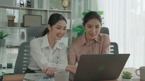 Deux jeunes femmes d'affaires enthousiastes travaillant ensemble dans le bureau