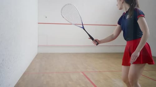 Young Lady in Red Tennis Skirt Improves Strokes with Racket