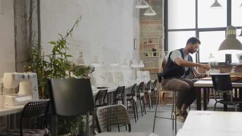 Male Dressmaker Sewing Pieces of Fabric by Hand in Atelier