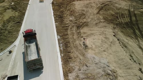 Construction Truck Tipping Dumping Gravel on Road Construction Site Drone Above View Footage