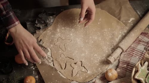 Close-up of a woman's hand making gingerbread cookies in the form of a Christmas tree and a gingerbr