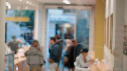 Coffee shop visitors waiting in queue, view through the glass