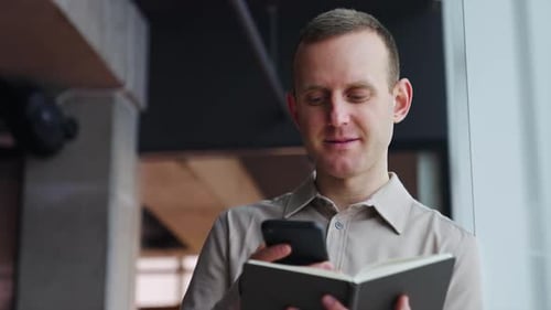 Adult Using Phone and Notebook Indoors